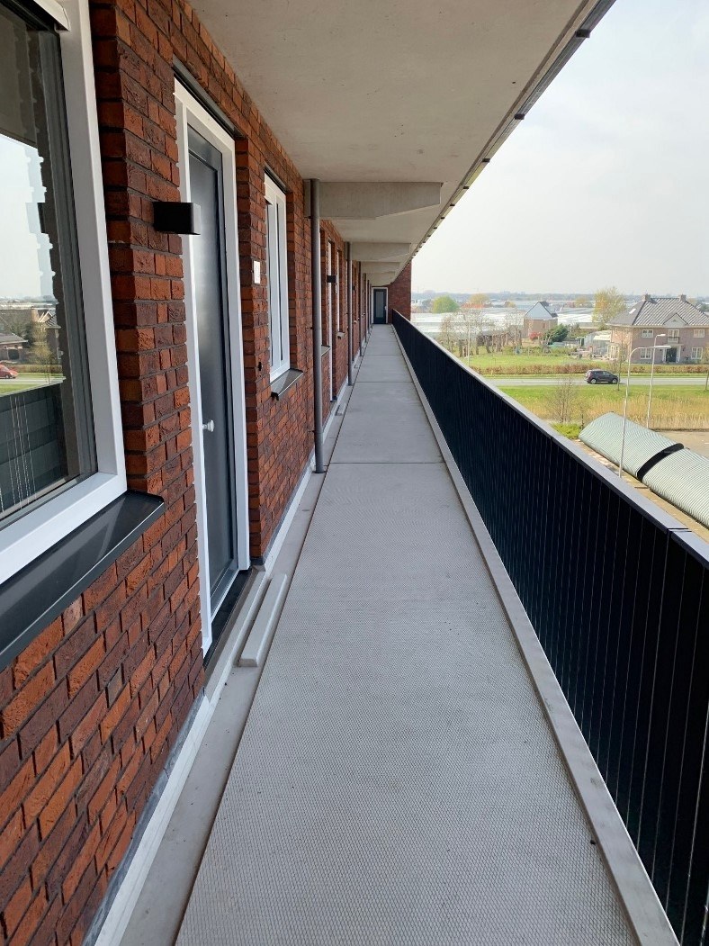 Schone galerij van een appartementencomplex met voordeuren en een zwarte balustrade