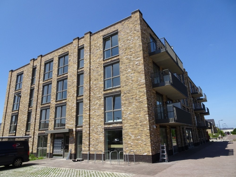 Appartementengebouw van gele baksteen met balkons aan een straat