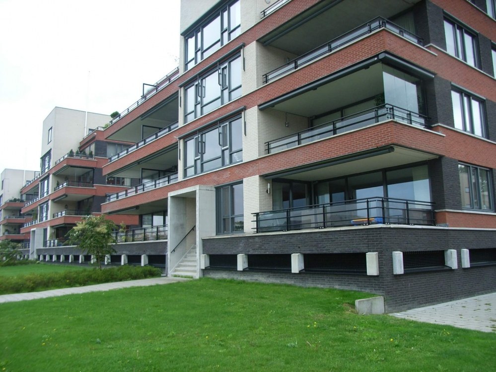 Appartementencomplex met rode gevelbanden en balkons aan een grasveld